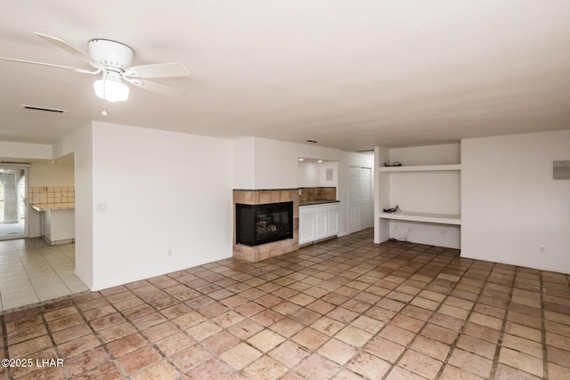 unfurnished living room featuring a ceiling fan, a fireplace, and visible vents