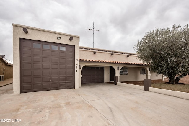 view of front facade with central AC unit, stucco siding, an attached garage, and driveway