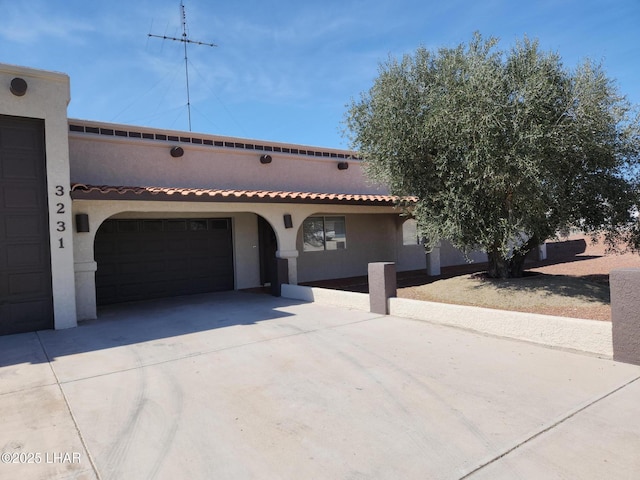 mediterranean / spanish-style home featuring a tiled roof, stucco siding, driveway, and a garage