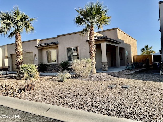 view of front facade featuring stucco siding, stone siding, an attached garage, and a tiled roof