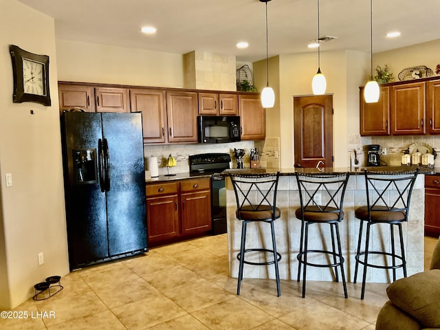 kitchen featuring a breakfast bar, black appliances, dark countertops, and visible vents