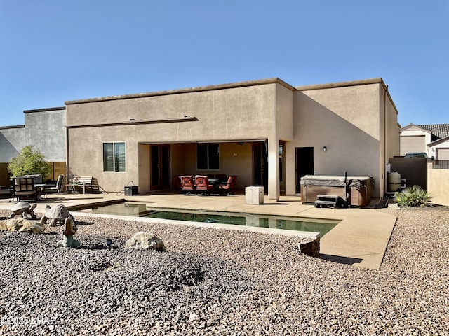 rear view of property with a patio area, a pool, stucco siding, and a hot tub