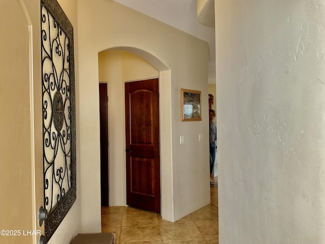 corridor featuring light tile patterned floors and arched walkways