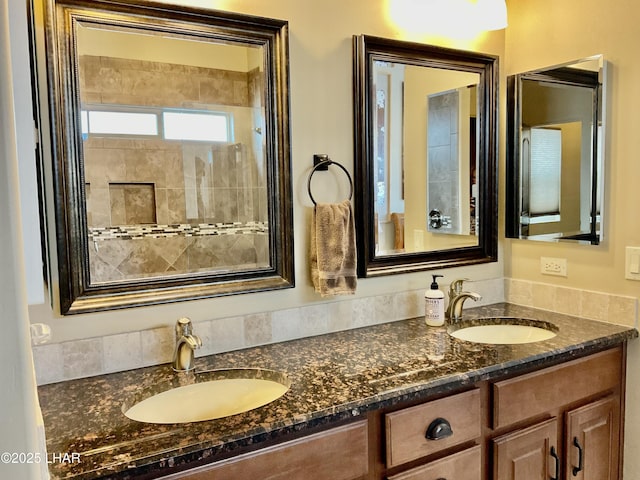 full bath with a sink, tiled shower, and double vanity