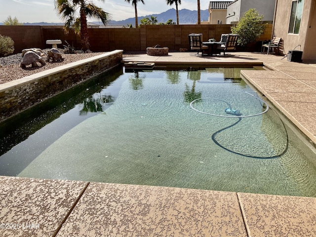 view of pool with a patio, a fenced backyard, a mountain view, and a fire pit