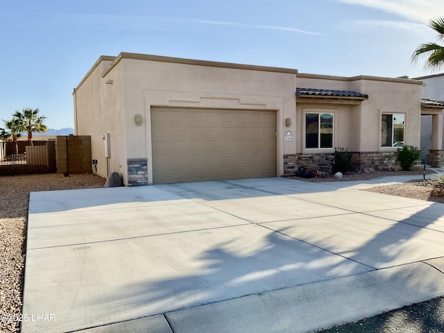 southwest-style home with stucco siding, stone siding, concrete driveway, and an attached garage