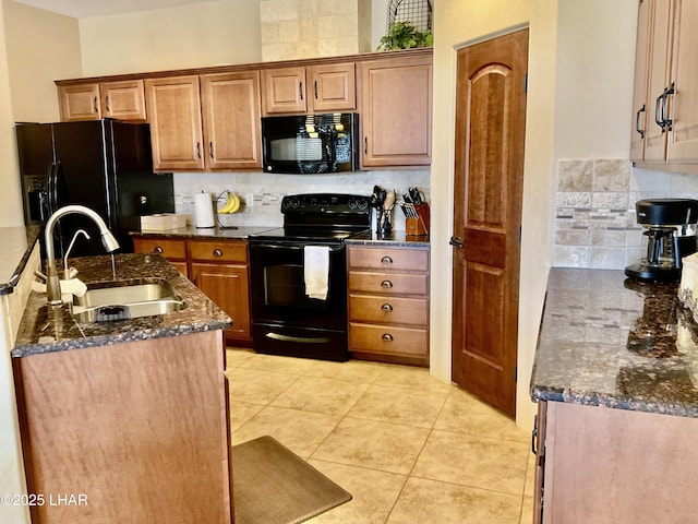 kitchen featuring backsplash, dark stone counters, light tile patterned floors, black appliances, and a sink