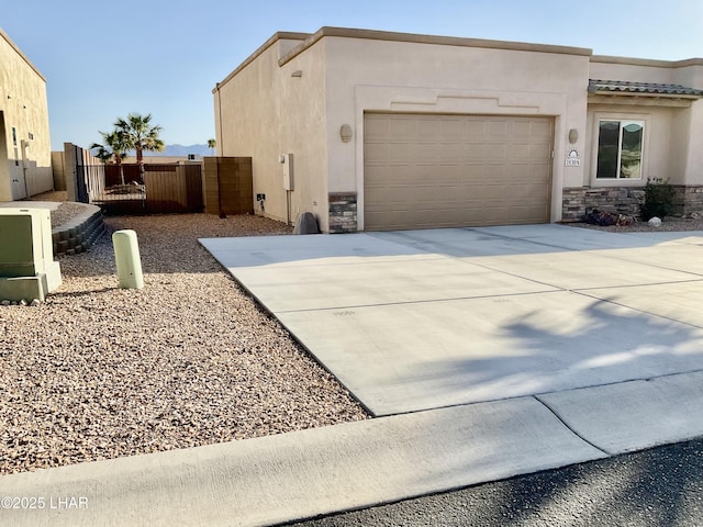 view of side of property with stucco siding, stone siding, driveway, and a gate