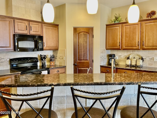 kitchen with tasteful backsplash, hanging light fixtures, a breakfast bar area, and black appliances