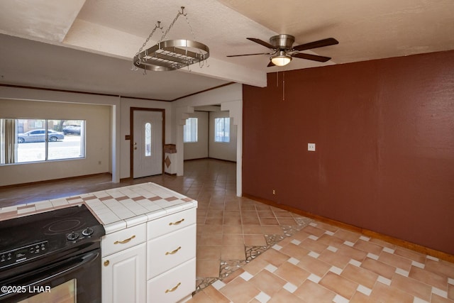 1116 W 4th St, Parker, AZ 85344 - kitchen with electric range, tile counters, white cabinetry, ceiling fan, and light tile patterned floors