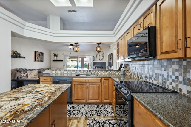 kitchen with visible vents, black appliances, a sink, open floor plan, and brown cabinetry