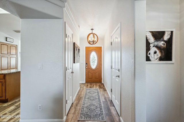 doorway featuring light wood-type flooring, baseboards, and a notable chandelier