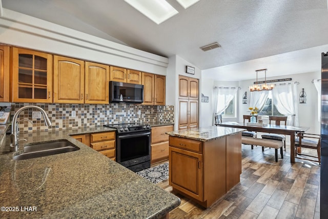 kitchen featuring stainless steel microwave, visible vents, electric range oven, vaulted ceiling, and a sink