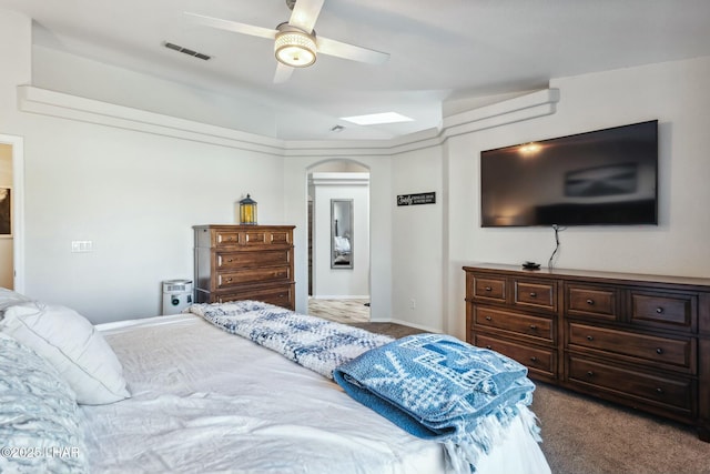 bedroom featuring dark colored carpet, visible vents, arched walkways, and ceiling fan