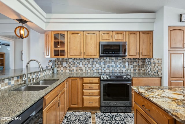 kitchen with a sink, stainless steel microwave, light stone countertops, and electric range oven