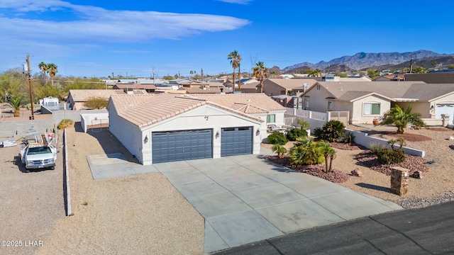 single story home with an attached garage, a residential view, stucco siding, concrete driveway, and a mountain view