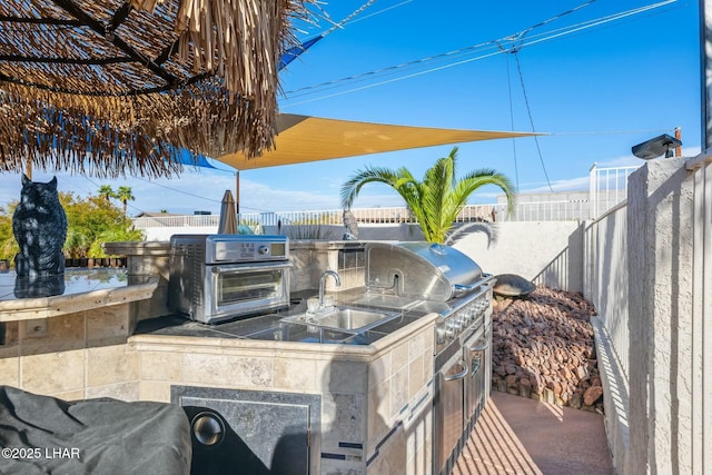 view of patio / terrace with area for grilling, a grill, a fenced backyard, and a sink