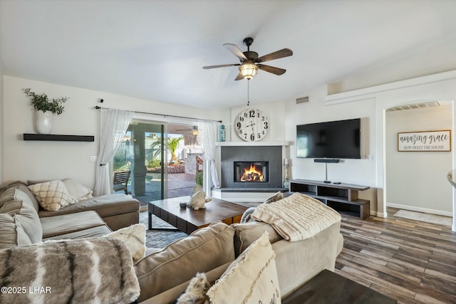 living room with visible vents, wood finished floors, baseboards, ceiling fan, and a tile fireplace