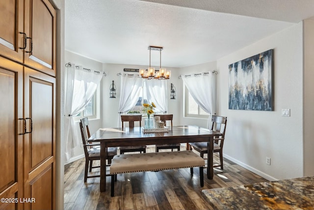 dining space with dark wood finished floors, a notable chandelier, a textured ceiling, and baseboards