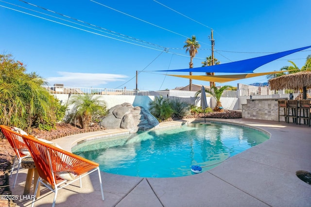 view of pool with a fenced backyard, a patio, a fenced in pool, and outdoor dry bar