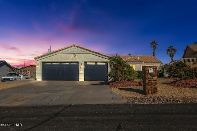 single story home featuring concrete driveway, a garage, and stucco siding