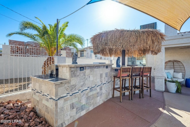 view of patio / terrace featuring outdoor dry bar and fence