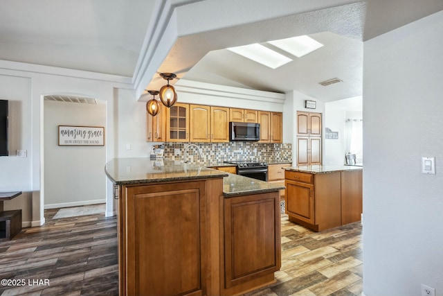 kitchen with backsplash, visible vents, dark stone countertops, and stainless steel appliances