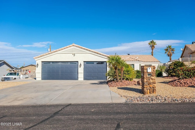 view of front facade featuring a tile roof, a garage, driveway, and stucco siding