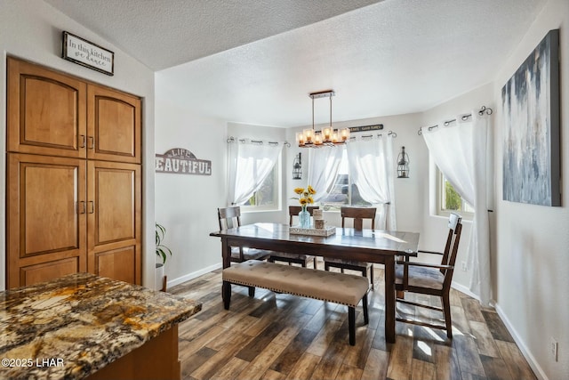 dining space featuring a textured ceiling, baseboards, dark wood-style flooring, and a chandelier