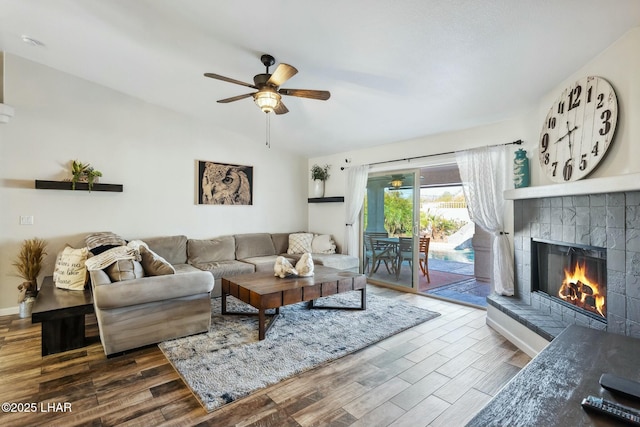 living area featuring baseboards, wood finished floors, a fireplace, and a ceiling fan