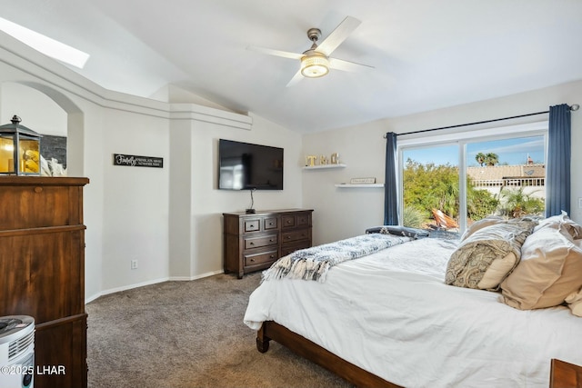 carpeted bedroom with baseboards, vaulted ceiling with skylight, and a ceiling fan