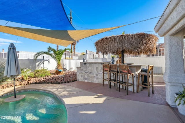 view of swimming pool featuring a patio, a fenced backyard, a fenced in pool, and outdoor dry bar