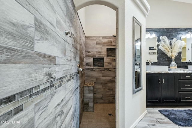 bathroom featuring a sink, tiled shower, and double vanity