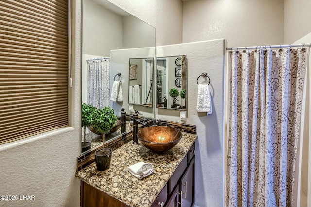 full bathroom featuring a shower with curtain, a textured wall, and vanity