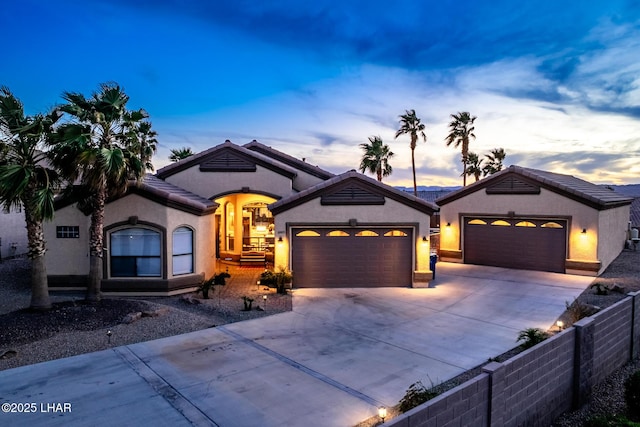 view of front of house featuring an attached garage, fence, concrete driveway, a tiled roof, and stucco siding