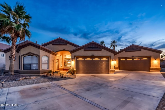 mediterranean / spanish-style home with a garage, concrete driveway, and stucco siding