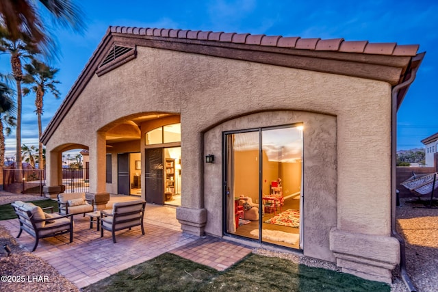 rear view of house featuring a patio area, fence, and stucco siding