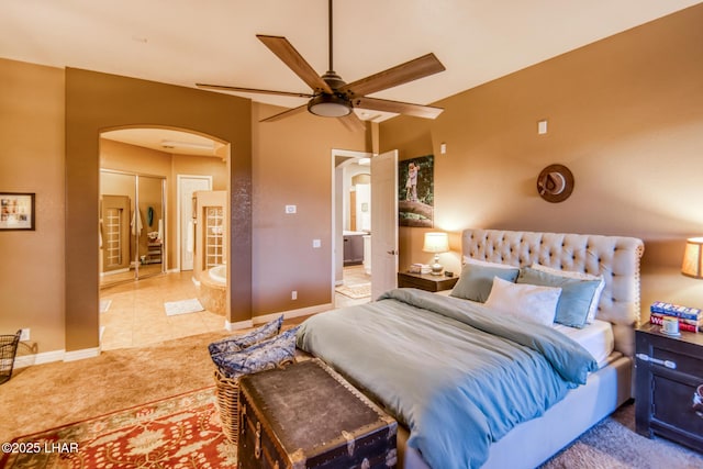 bedroom featuring carpet, arched walkways, baseboards, and tile patterned floors