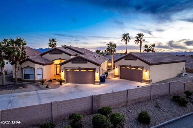 view of front facade with concrete driveway, an attached garage, a tile roof, and stucco siding