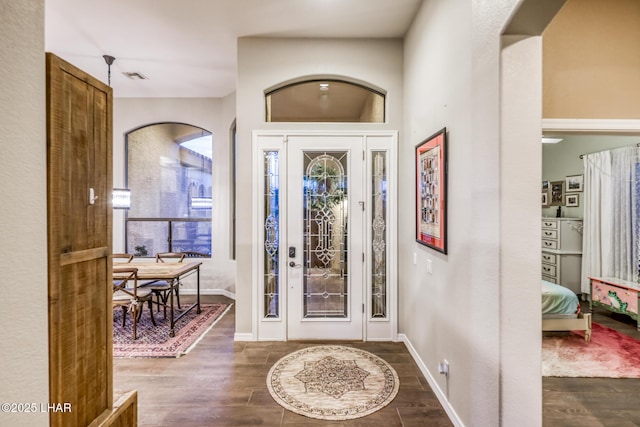 entryway featuring arched walkways, visible vents, dark wood finished floors, and baseboards