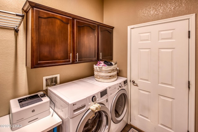 washroom featuring a textured wall, separate washer and dryer, and cabinet space