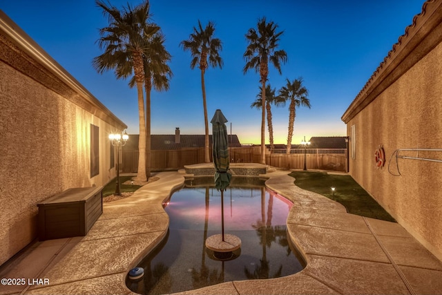 pool at dusk with a patio, a fenced backyard, and a fenced in pool