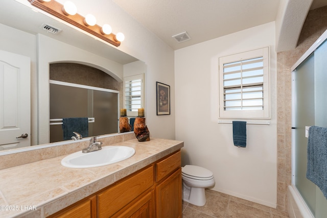 bathroom with visible vents, toilet, a shower with shower door, vanity, and tile patterned floors