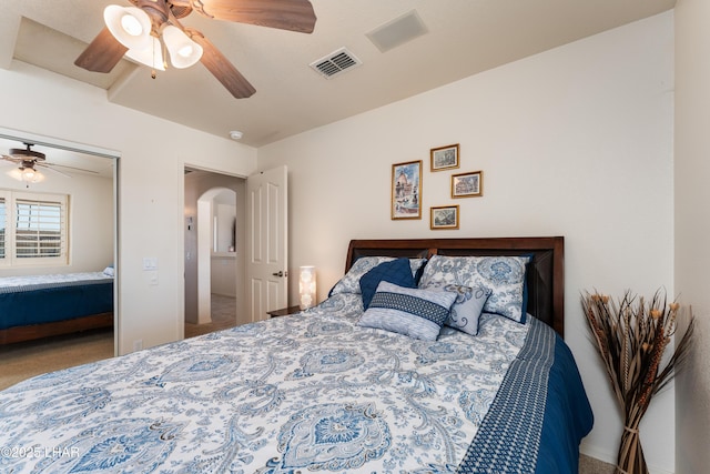 bedroom featuring arched walkways, visible vents, ceiling fan, and carpet