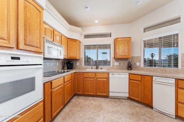 kitchen featuring light countertops, white appliances, backsplash, and a sink