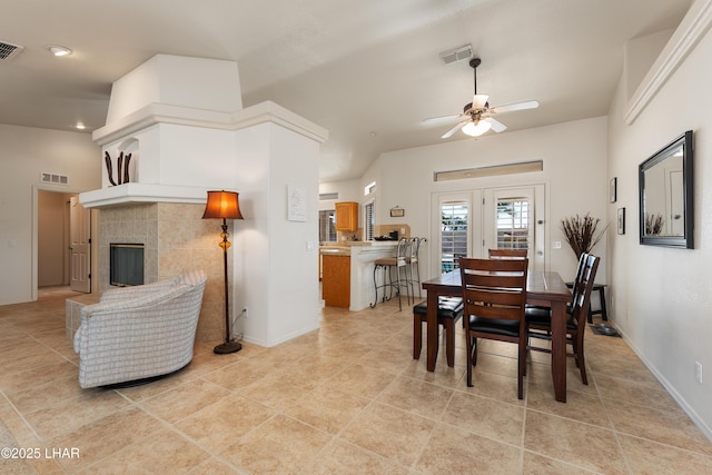 dining area featuring ceiling fan, visible vents, and a tile fireplace