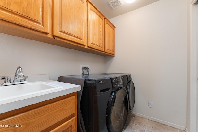 clothes washing area featuring cabinet space, visible vents, a sink, separate washer and dryer, and baseboards