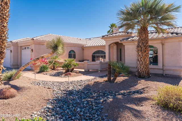 mediterranean / spanish-style home featuring a garage, a tile roof, and stucco siding