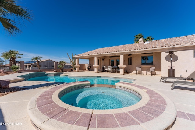 view of swimming pool with a pool with connected hot tub, a patio, and fence