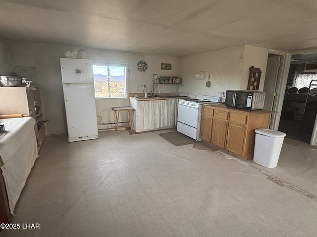 kitchen featuring a peninsula, white appliances, a sink, light floors, and dark countertops